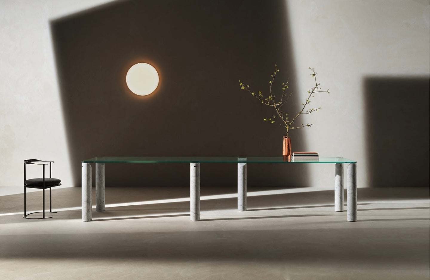 Isos Table by Piero Lissoni embodies transparency and visual lightness. Its cylindrical legs play the lead design role. A load bearing element is grafted to the top via a steel plate, achieving a unique design junction. ‘The Isos table has legs cut at 35 degrees. As if it were a pencil, I pointed the legs at the nook where the tops rest on them to lessen the impact and to exaggerate their static and architectural quality. It can be made in many materials, in glass, in wood, with marble legs. But the interesting thing is the tension that is built between these pencil-columns and the top.’ – Piero Lissoni
