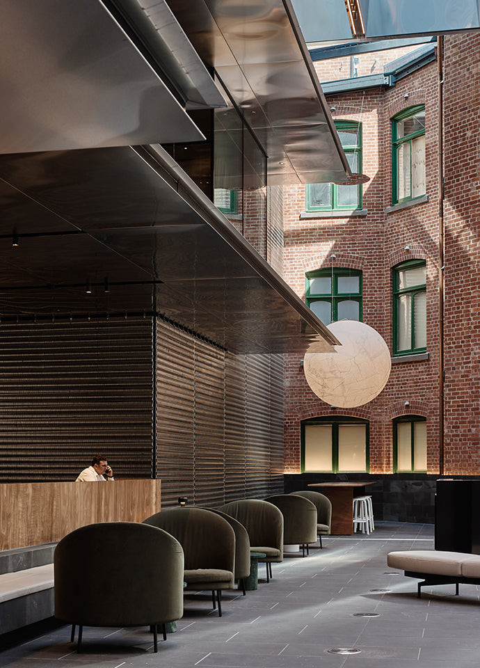 All textures and warm colour, the raw red bricks of a neighbouring building, the Jim armchair in a forest green velvet by Arflex, and the Container table in wood by Moooi. Photography © Peter Bennetts c/o Hassell.
